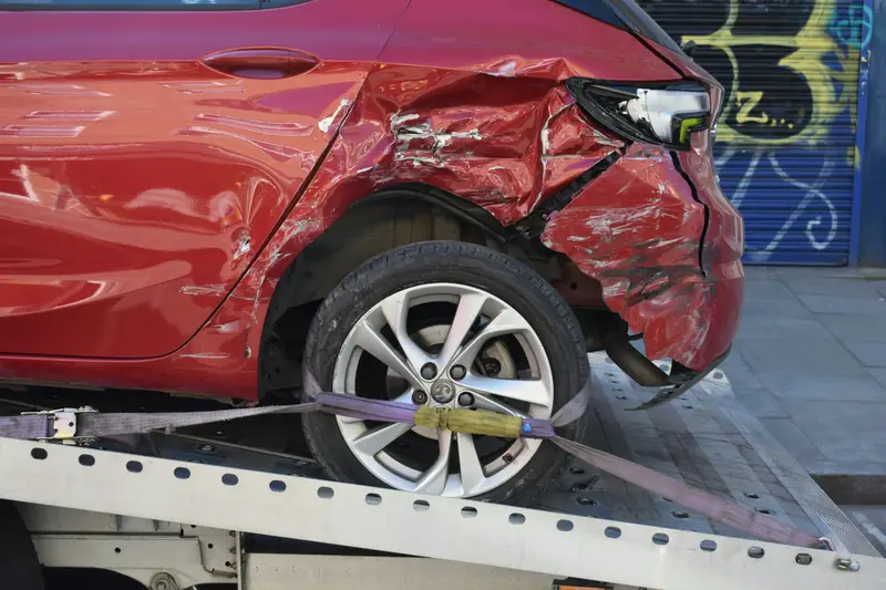 Rotes Auto mit Unfallschaden auf einem Abschleppwagen