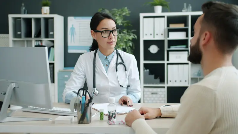 Ärztin im Sprechzimmer im Gespräch mit einem Patienten