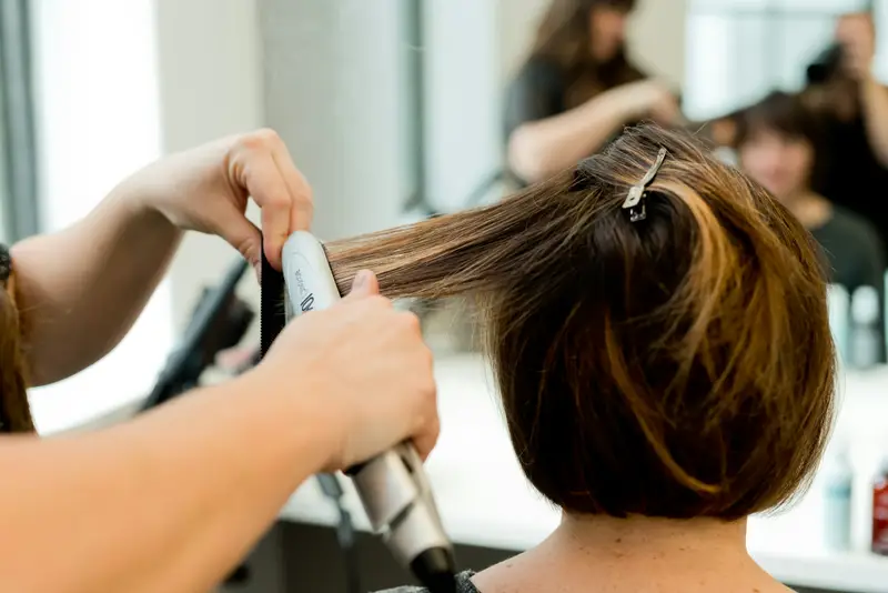 Haar wird im Salon mit dem Glätteisen gestylt