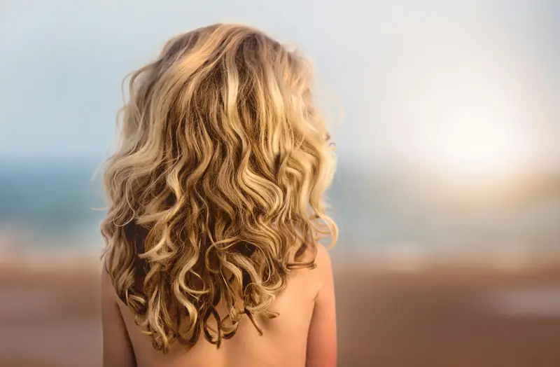 Lange, blonde Locken von hinten im warmen Licht