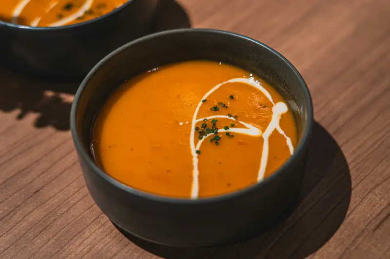 Kürbissuppe mit einem Klecks Sahne in einer dunklen Schale