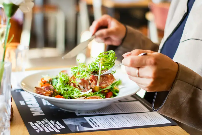 Mittagsgericht mit Salat, gegessen am Holztisch