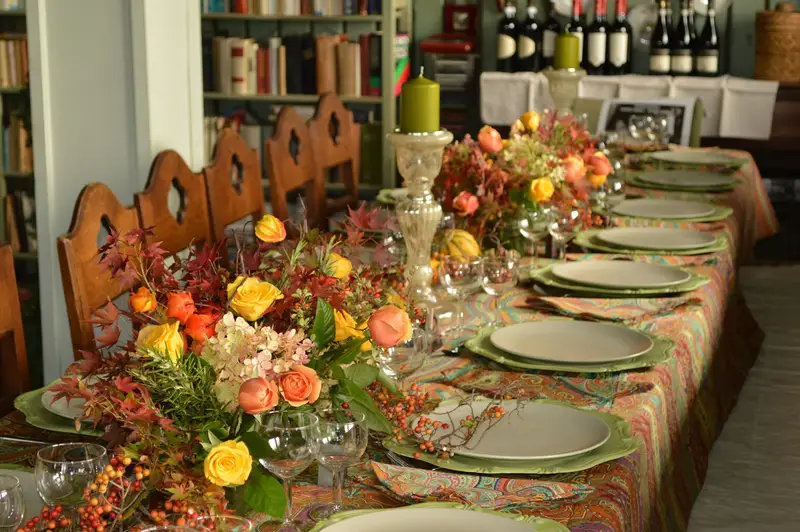 Lange Tafel mit Blumen im Nebenraum, im Regal Weinflaschen