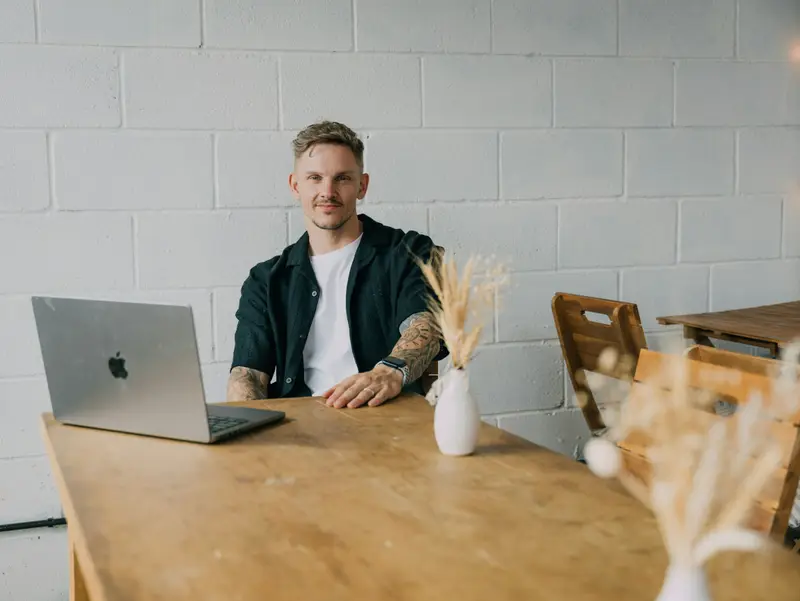 Gründer am Laptop an einem langen Holztisch