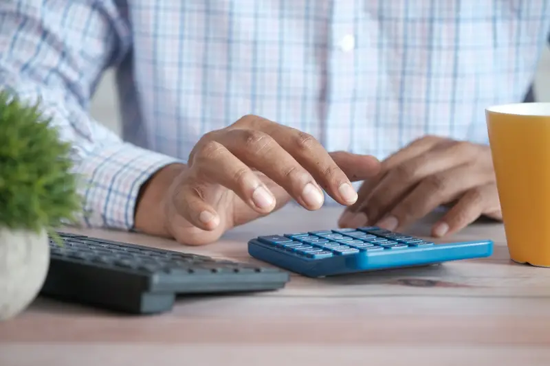 Hände mit Taschenrechner und Tastatur am Schreibtisch