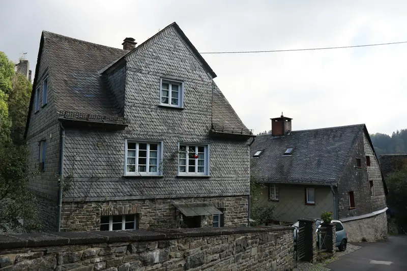 Zwei alte Häuser mit Schieferdach und Schieferfassade an einer Gasse, bedeckter Himmel